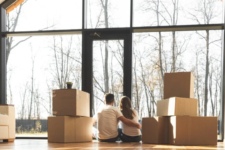 emotions of selling a home, couple sitting on floor of house with moving boxes